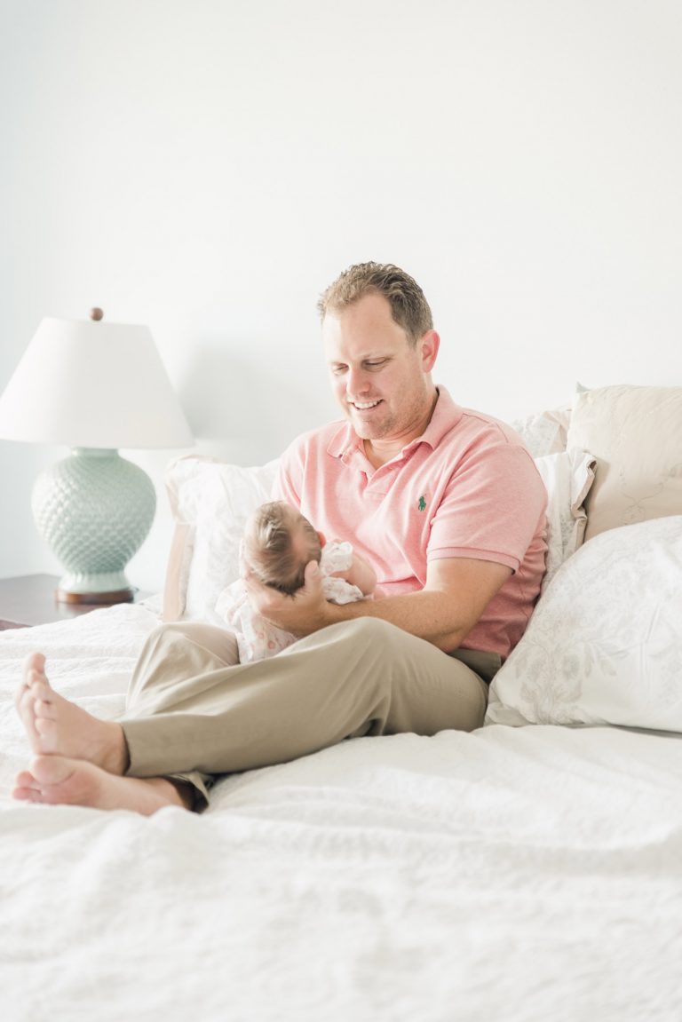 lifestyle newborn photos of daddy holding baby girl and looking down at her