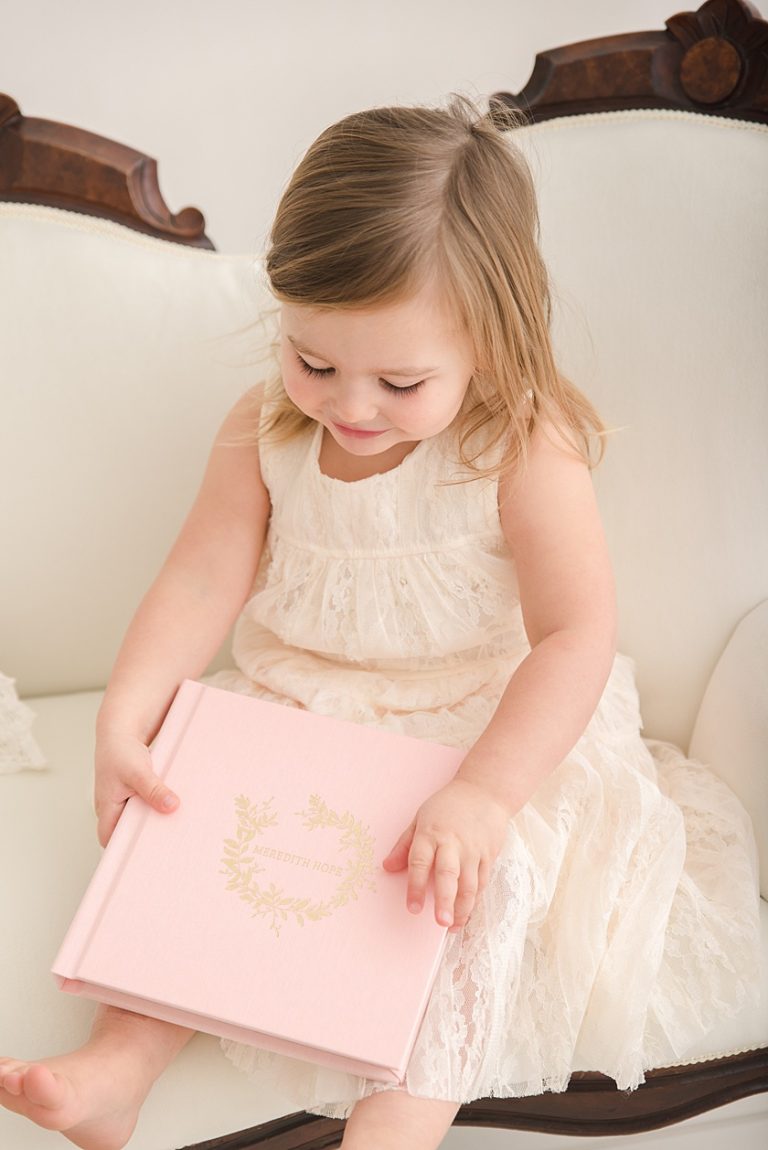 Little Girl Holding Newborn Album on a Settee