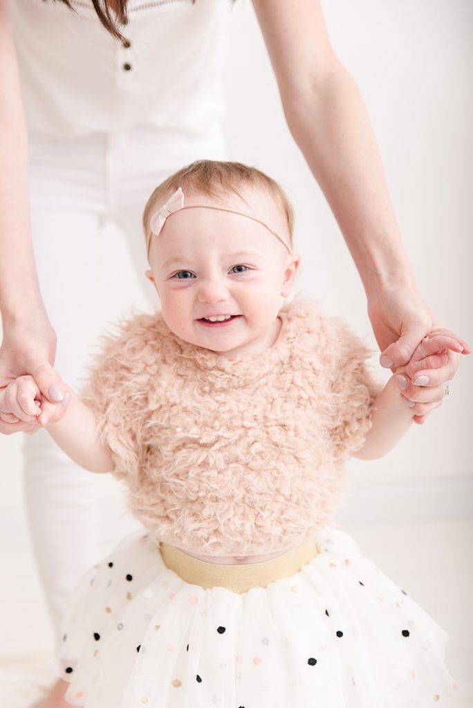 One Year Old Little Girl wearing tutu and faux fur shirt for First Birthday Photos