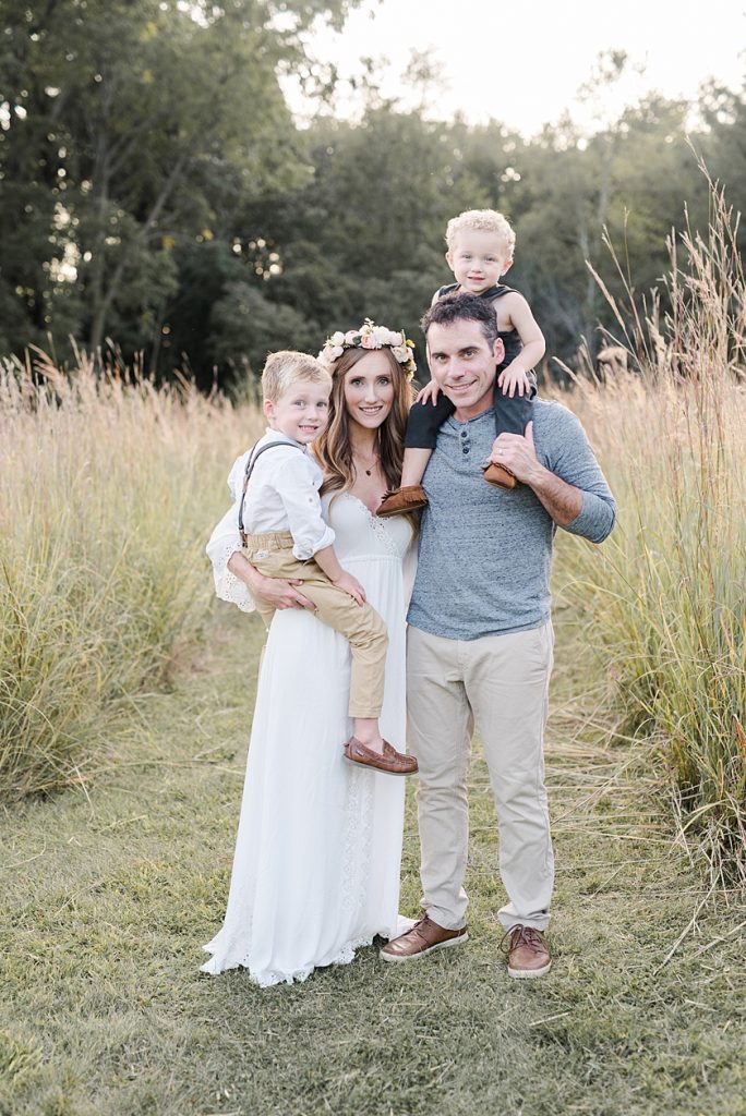 Mom and Dad holding two little boys in the private field for a family photo session