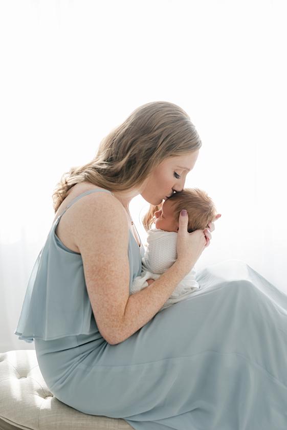 new mom kisses baby boy by iowa city newborn photographer meghan goering photography