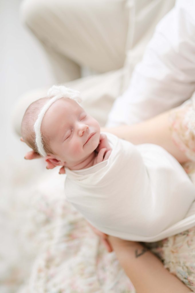 Precious newborn in light and airy studio being held by parents
