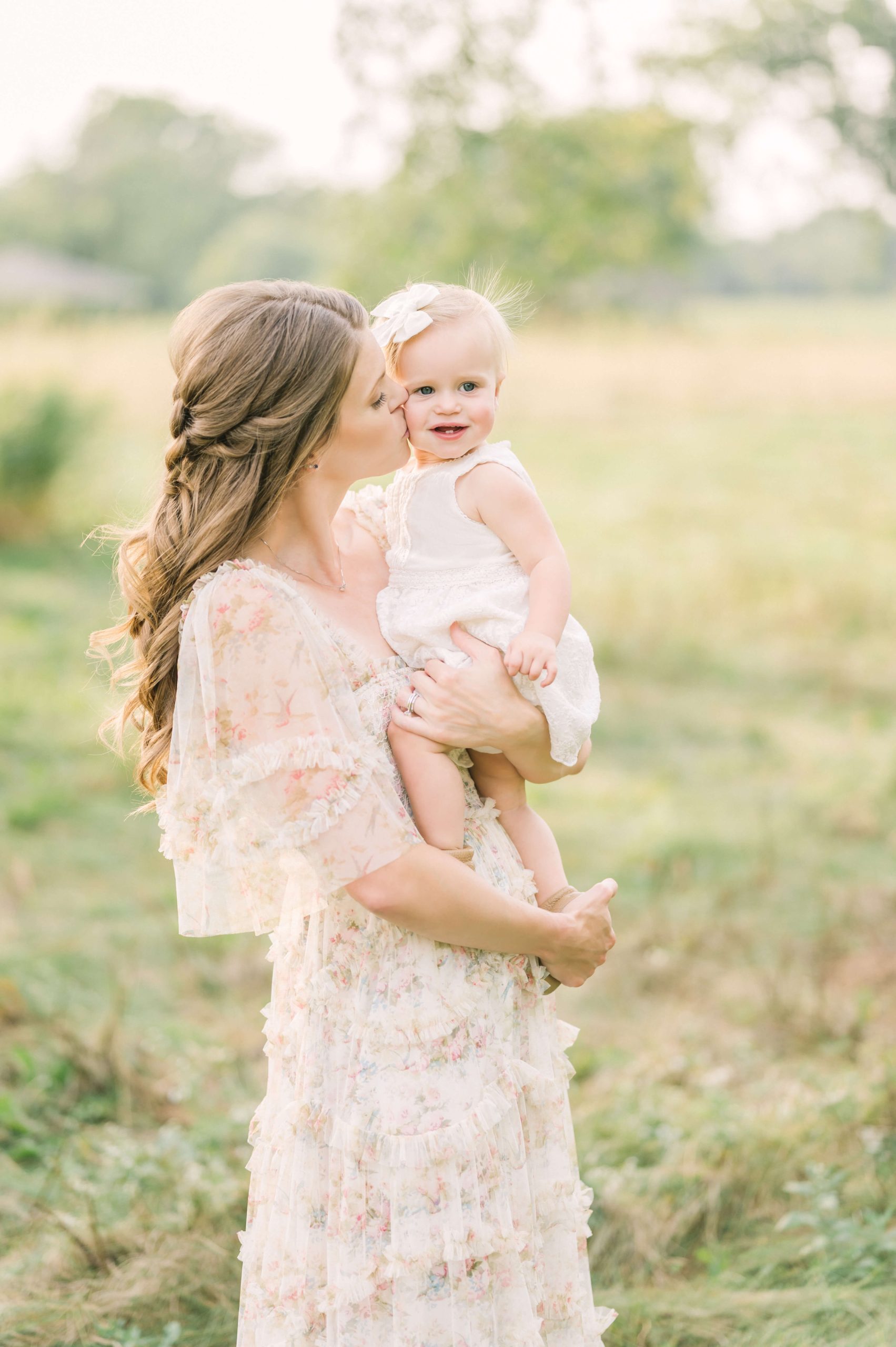 beautiful mother in outdoor field wearing needle and thread dress with daughter who is one year old